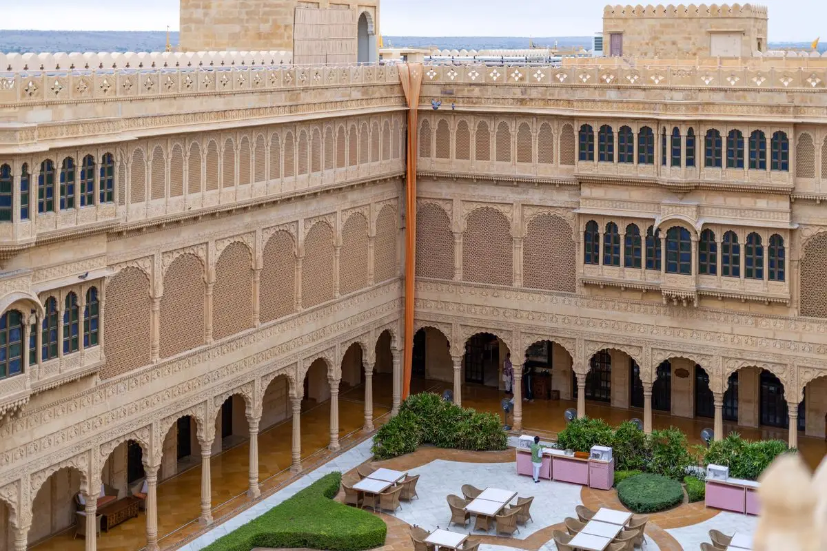 Sandstone courtyard of a heritage hotel in Jaisalmer, Rajasthan, with carved arches, balconies and guest tables below
